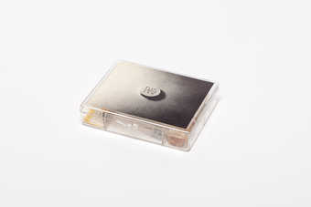 .1 - a 7-compartment clear plastic box with a Maciunas-designed label attached to the lid,...
