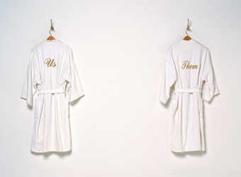 two white terry cloth bathrobes one with "US" the other with "THEM"...