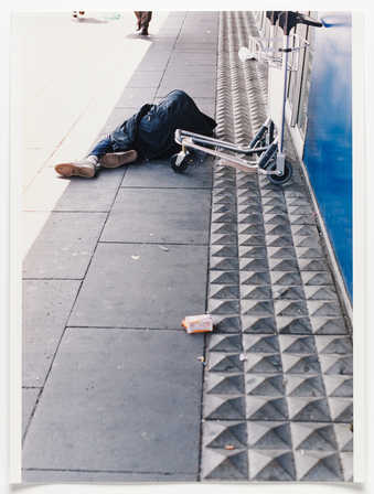An iimage of a homeless person sleeping next to pointed concrete pavers, installed to discourage