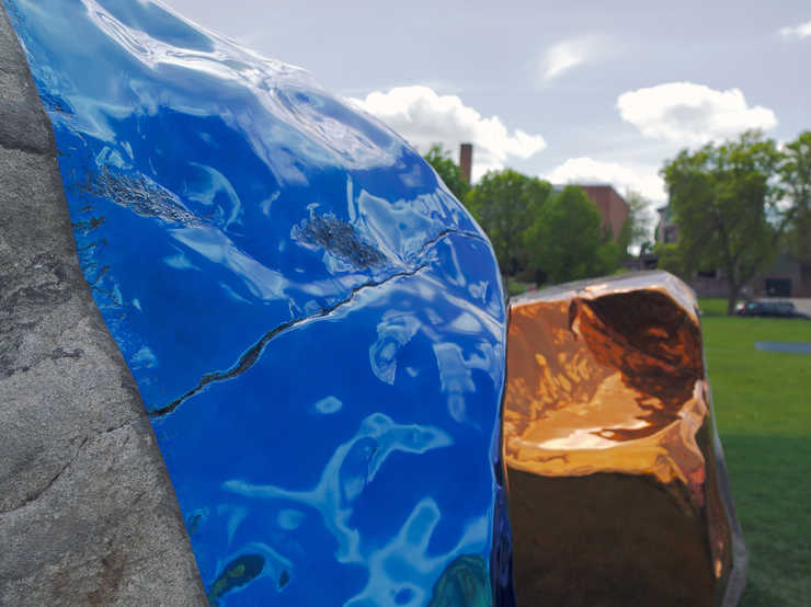 Four large boulders, each containg a sheer of mirror polished, colored stainless steel, The...