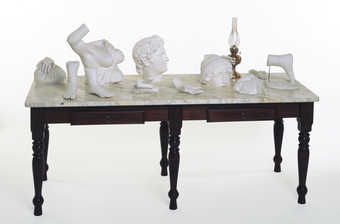 plaster cast body fragments and a gas lamp on a marble topped table