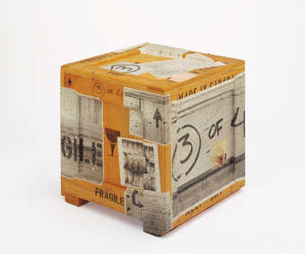 A wooden crate with black-and-white photographs stapled to the outside