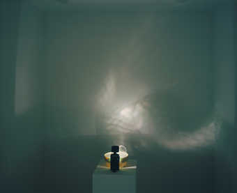 round turntable rotates with clear plastic cup and flashlight projects light through cup onto wall