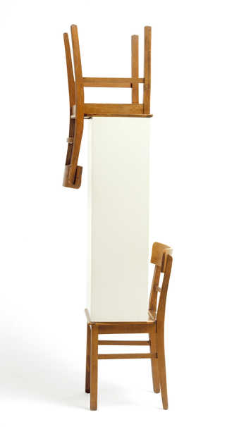 A chair supporting a pedestal with another inverted chair on top.