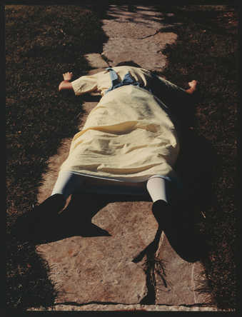 An image of a young woman in a yellow dress and white tights falling down steps.
