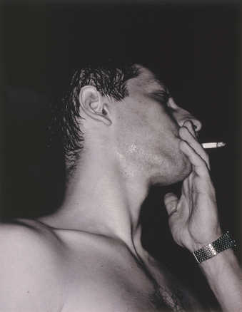 profile shot of a man's head and hand while smoking a cigarette